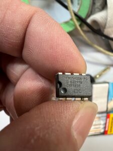 Close-up of a hand holding a small integrated circuit chip.